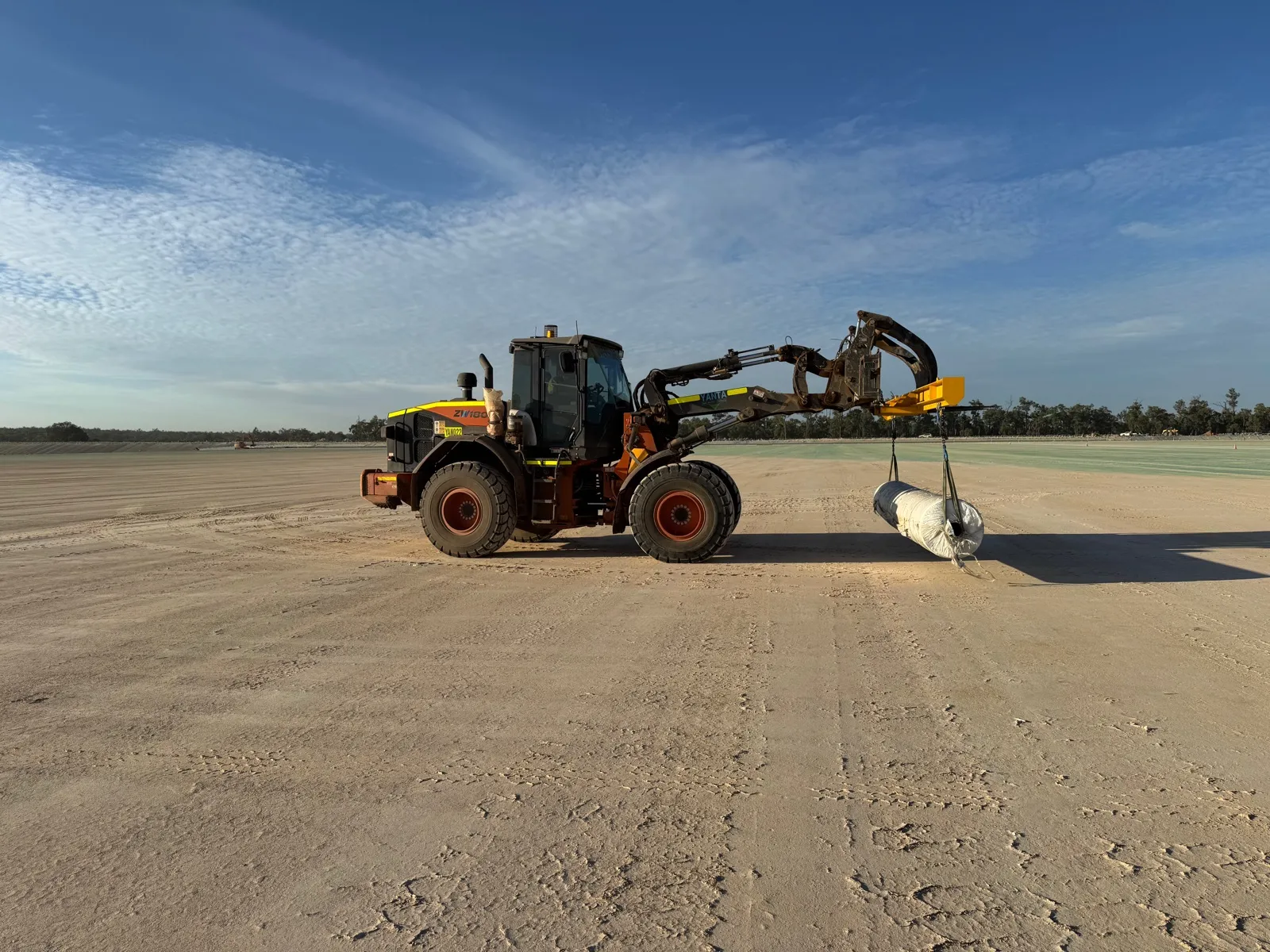 Loader carrying materials across a prepared pad